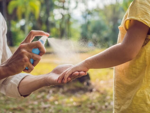 dad and son use mosquito spray.Spraying insect repellent on skin outdoor